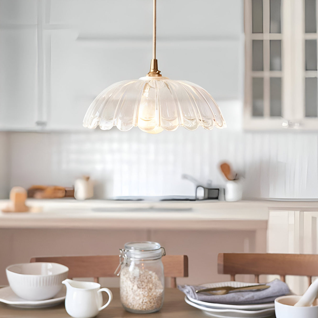 Endon Bevcombe clear glass pendant shade with scalloped domed form and brass fitting, hung above a kitchen island and dining table setting.