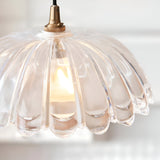 Endon Bevcombe scalloped clear glass domed pendant shade illuminated by a warm filament lamp, suspended from an antique brass fitting and braided black flex.