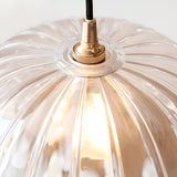 Close-up of the Endon Bevcombe clear glass pendant shade showing its scalloped domed form and brass lamp holder with black braided flex.