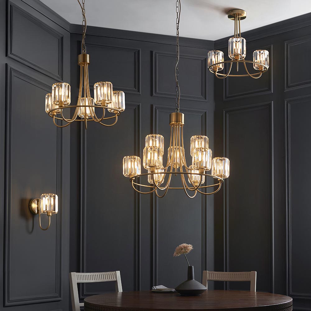 Clementine 9 Light Tiered Chandelier in antique brass with faceted crystal glass shades, shown centred in a dark panelled dining room.