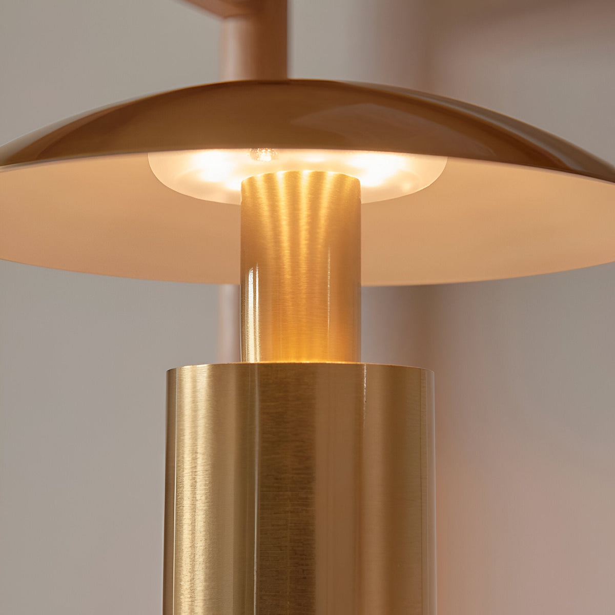 Close-up of the Cranbourne LED Table Lamp in brushed brass, showing the mushroom-style dome shade lit warm white above the cylindrical base.