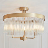 Endon Chatsworth 3 light semi-flush ceiling light in antique brass with a circular plate and tiered glass rod shades, shown fitted to a white ceiling.