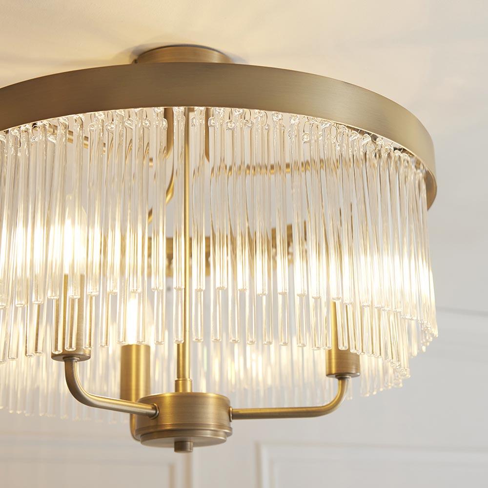 Endon Chatsworth 3 light semi-flush ceiling light in antique brass, with tiered clear glass rod shades below a circular ceiling plate.