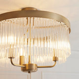 Endon Chatsworth 3 light semi-flush ceiling light in antique brass, with tiered clear glass rod shades below a circular ceiling plate.