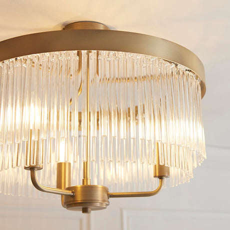 Endon Chatsworth 3 light semi-flush ceiling light in antique brass, with tiered clear glass rod shades below a circular ceiling plate.