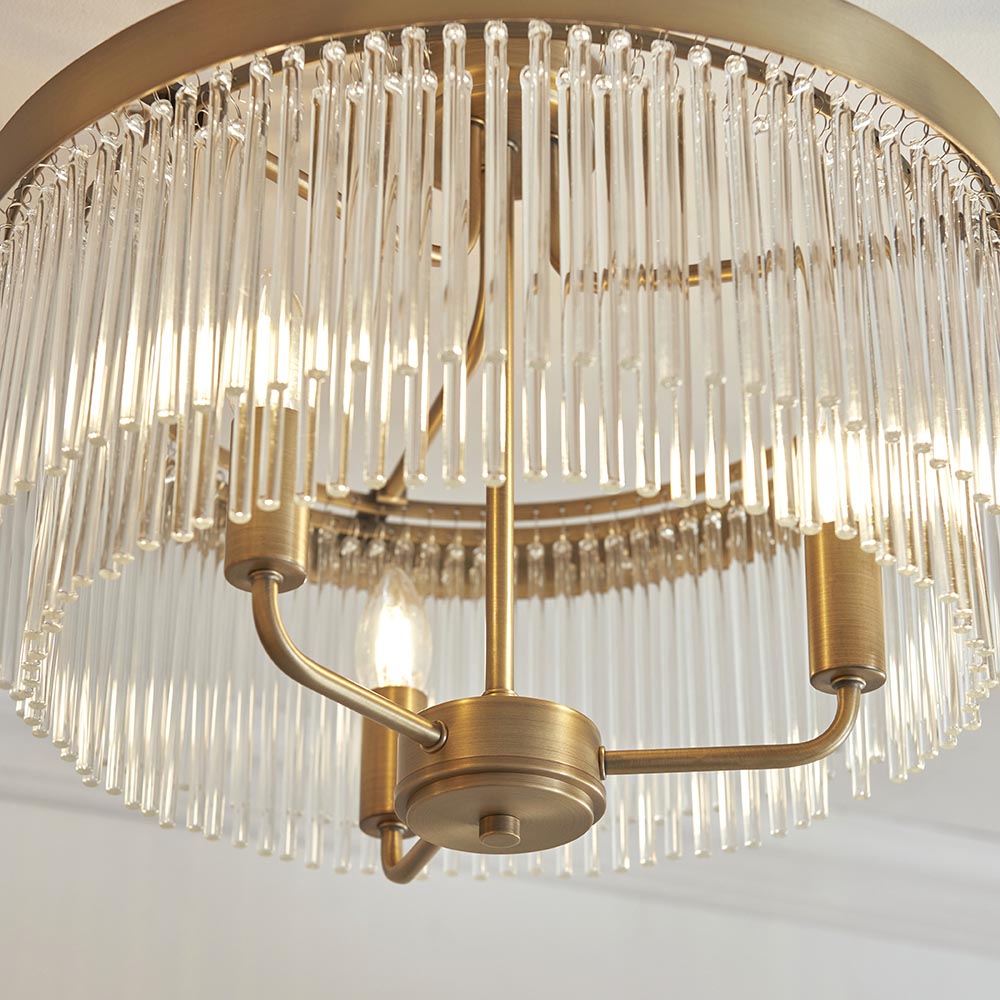 Close-up of the Endon Chatsworth 3 light semi-flush ceiling light in antique brass, showing tiered glass rods, central lit E14 lamp and circular fixing plate.