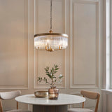 Endon Chatsworth 5 light pendant in antique brass with double tier of clear glass rods, hanging above a round marble dining table.