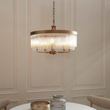 Endon Chatsworth 5 light pendant in antique brass with double tier of clear glass rods, suspended by chain above a dining table against panelled walls.