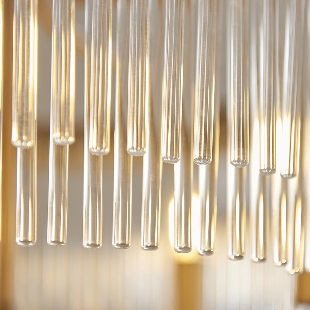 Close-up of the Endon Chatsworth 5 Light Pendant showing clear suspended glass rods in a double layer, lit by warm antique brass lamps.