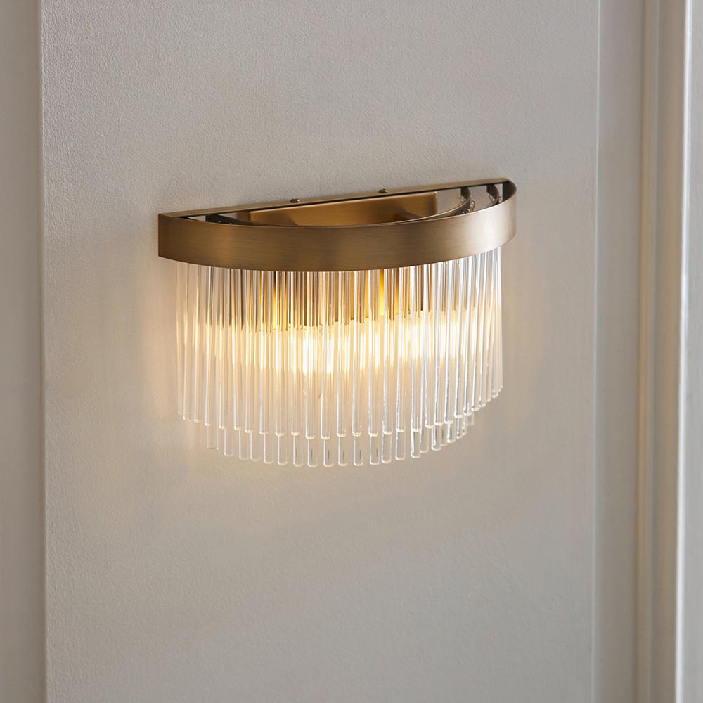 Chatsworth 2 Light Wall Light in antique brass, half-moon fitting with cascading clear glass rods, mounted on a white wall in a hallway setting.