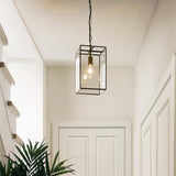 Endon Haddon Grand lantern pendant in brushed aged brass with clear glass panels and exposed E27 filament bulb, hung on a chain in a hallway.