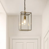 Endon Haddon Grand brushed brass pendant light with clear glass panels and exposed E27 filament bulb, suspended on a chain above a white panelled door.
