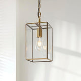 Haddon Pendant in brushed brass with a square lantern frame, clear glass panels, exposed E27 filament bulb, hung from a chain against a plain light wall.