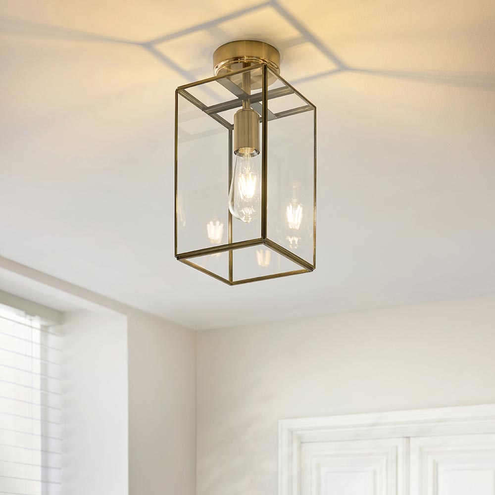 Endon Haddon flush ceiling light in aged brass with a rectangular glass lantern shade and single E27 bulb, mounted on a hallway ceiling.