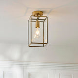 Endon Haddon flush ceiling light in aged brass with a rectangular glass box shade and single E27 bulb, mounted to a white ceiling above panelled walls.