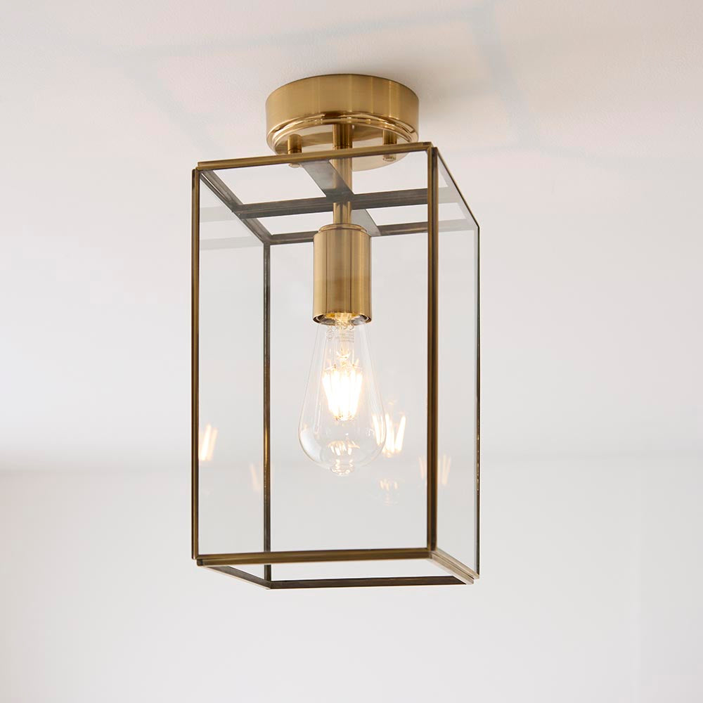 Endon Haddon flush ceiling light in aged brass with a rectangular clear glass shade and single E27 bulb, shown against a plain white ceiling.
