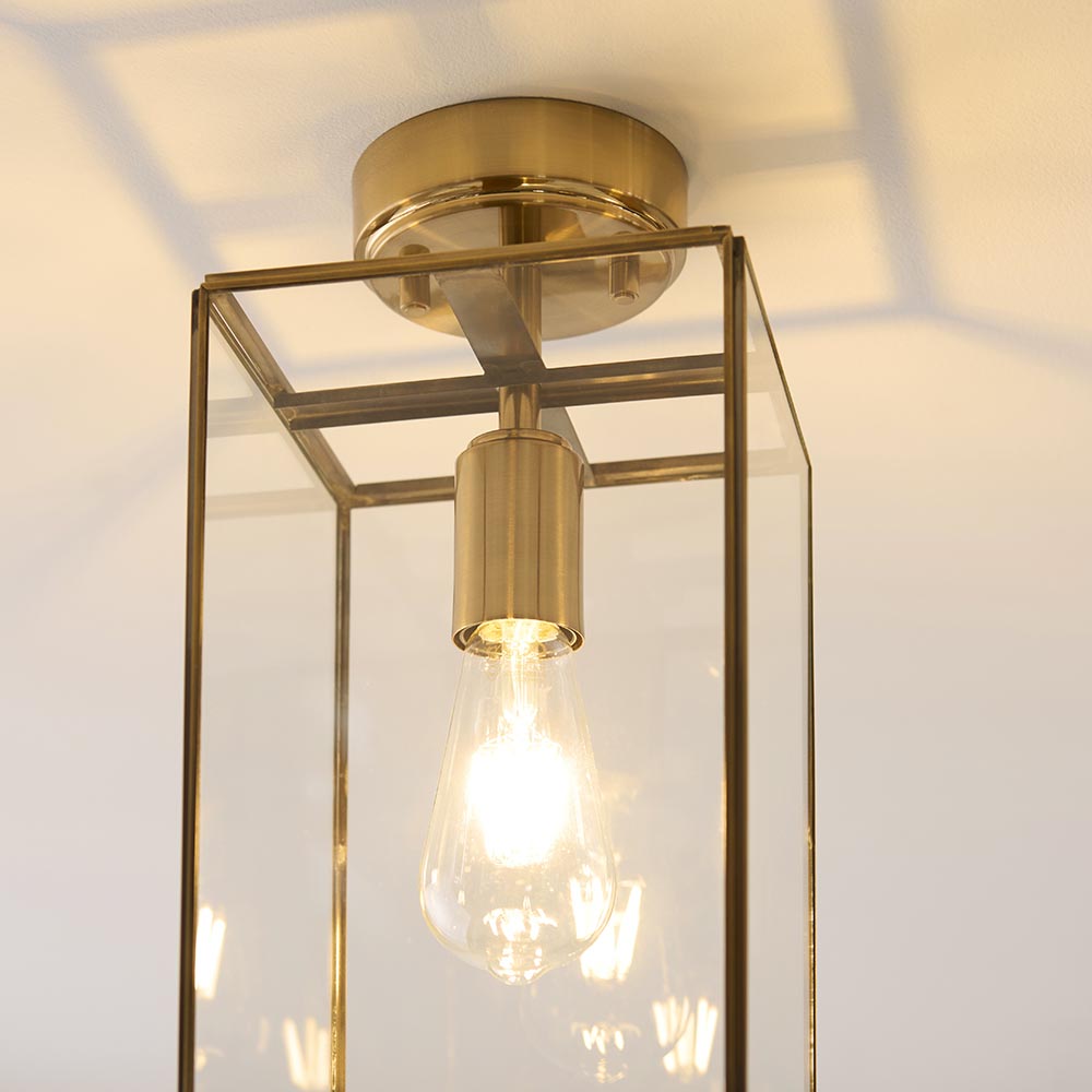 Endon Haddon flush ceiling light in aged brass with a rectangular glass shade and single E27 filament bulb, mounted to a white ceiling.