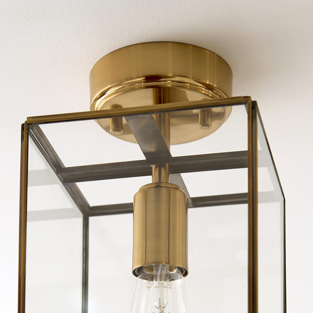 Close-up of the Endon Haddon flush ceiling light in aged brass, showing the compact ceiling mount, E27 lamp holder and glass box shade.