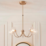 Bramwick 5 Light Pendant in antique brass with curved arms and clear twisted glass shades, hung from a ceiling rose in a panelled room.
