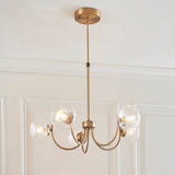 Bramwick 5 Light Pendant in antique brass with curved arms and clear twisted glass shades, shown hanging from a ceiling rose in a panelled room.