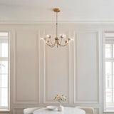 Endon Bramwick 7 light pendant in antique brass with curved arms and clear twisted glass shades, hanging in a panelled dining room between tall windows.