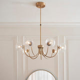 Endon Bramwick 7 light pendant in antique brass with curved arms and clear twisted glass globes, suspended from a telescopic stem above a round mirror.
