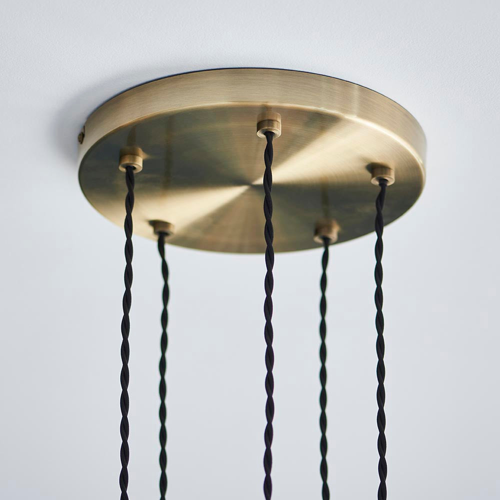 Close-up of Endon Georgiana 5 Light Cascade Pendant ceiling plate in antique brass, with five black twisted fabric cables dropping from the round disc.