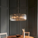 Endon Rothbury 8 Light Pendant in antique brass with ribbed glass drum shade, suspended from a chain over a dining table against dark panelled walls.
