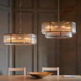 Two Endon Rothbury 8 Light Pendants in antique brass with ribbed glass panel shades, hung on chains above a dining table against a panelled grey wall.