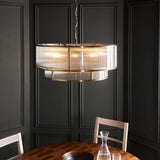 Endon Rothbury 8 light tiered chandelier in antique brass with clear ribbed glass panels, suspended from a chain in a dark panelled dining room.