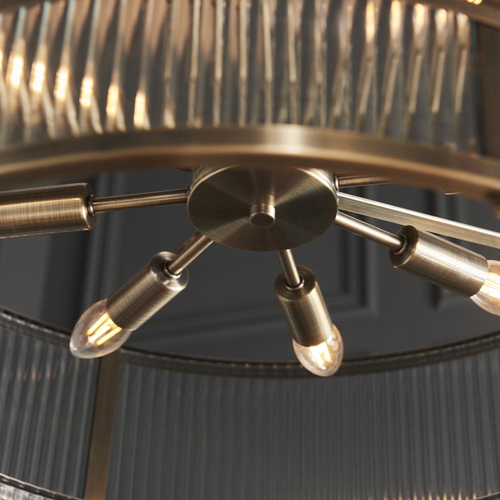 Close-up of the Endon Rothbury 8 Light Tiered Chandelier in antique brass, showing the central hub, radiating arms, E14 bulbs and ribbed glass panels.