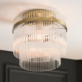 Endon Beaumont flush ceiling light in antique brass, with tiered glass rod shade mounted against a white ceiling above a dark panelled wall.