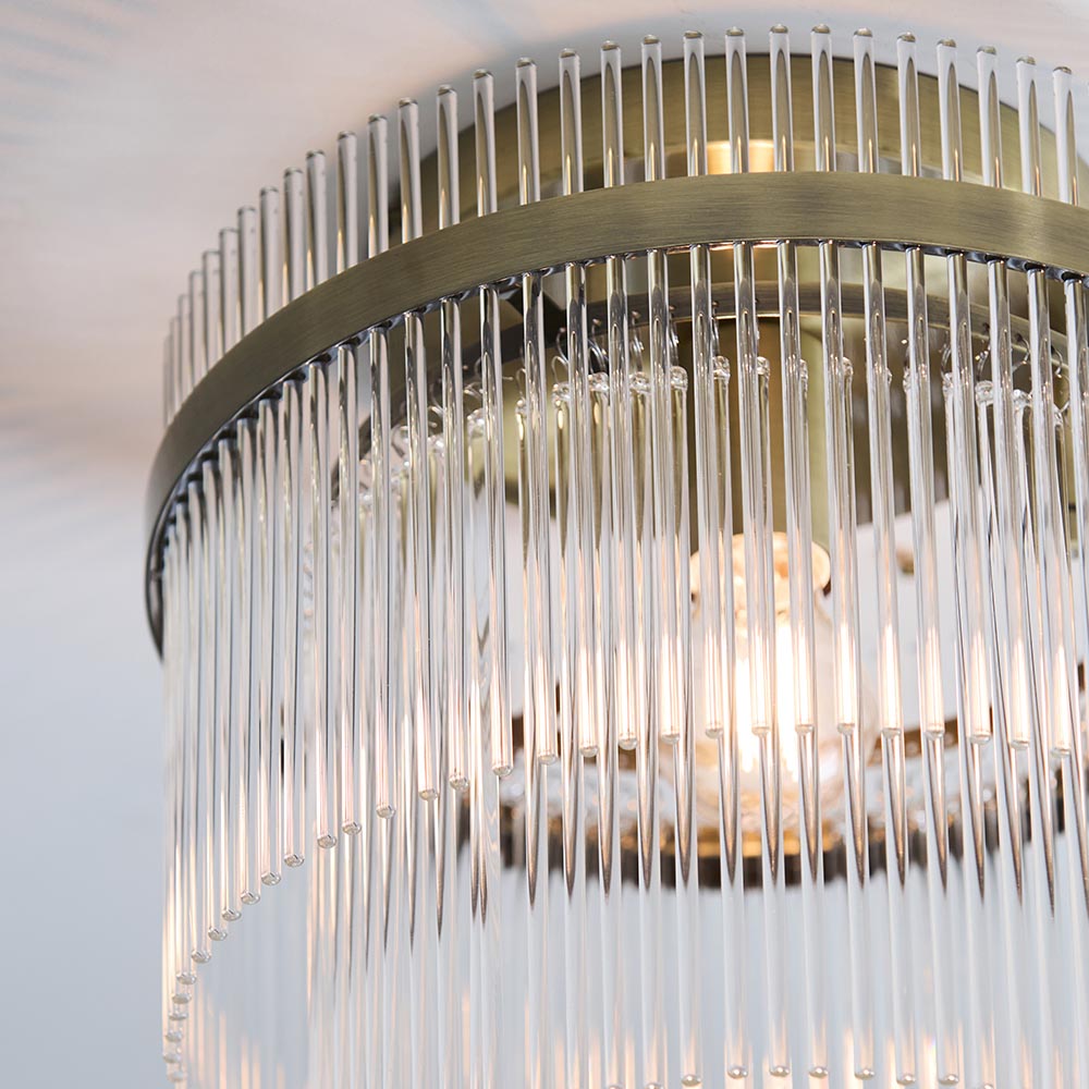 Close-up of Endon Beaumont flush ceiling light in antique brass, showing the tiered glass rod shade, lit E27 lamp and aged brass band.