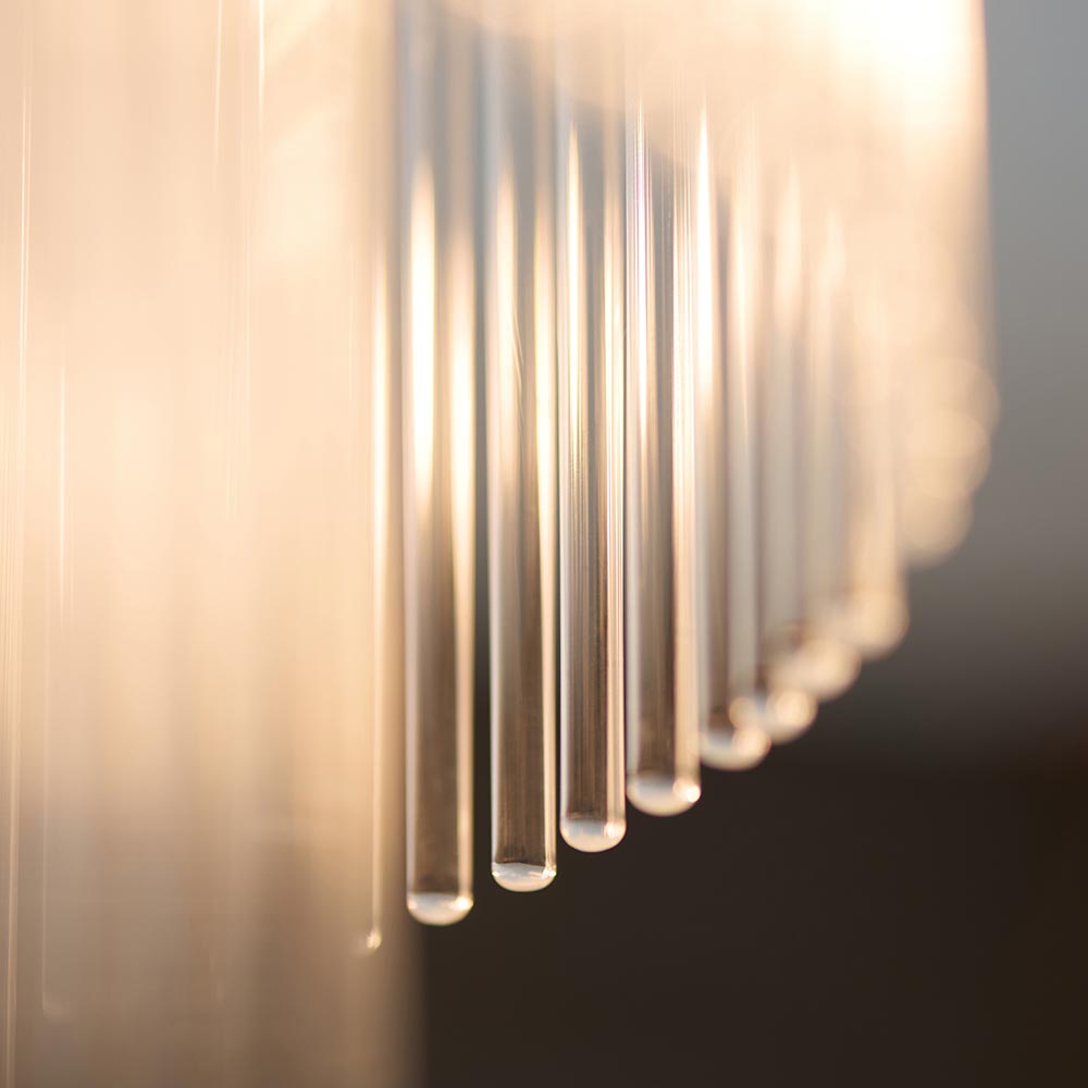Close-up of the Endon Beaumont flush ceiling light's glass rods, backlit to show warm amber tones along the clear vertical shade elements.