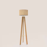 Breeze Fabric Drum Tripod Floor Lamp with a natural fibre drum shade on slim wooden tripod legs braced in gold-finish brass, shown against a plain light background.
