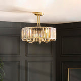 Fairfax 3-light semi-flush ceiling light in antique brass, round crystal glass shade with looping brass arms, shown mounted in a dark panelled room.