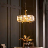 Fairfax 5 Light Pendant in antique brass with clear cut glass rods around a circular frame, shown hanging above a dining table in a dark panelled room.