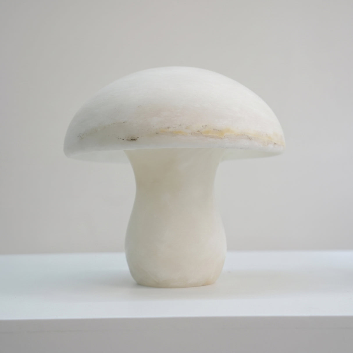 Morfia Small Mushroom Alabaster Table Lamp in Soft White, showing the carved dome-and-stem silhouette in natural veined alabaster against a plain light background.