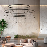 Skybell Circle Iron Ring LED Pendant Light in Ebony Black, three tiered rings with cone-shaped LED heads on slim stems, shown above a living room seating area.