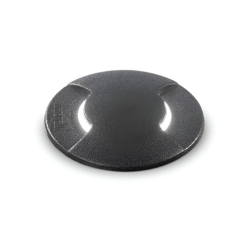 A round, black camera lens cap with a textured surface is displayed against a plain white background. Designed for durability, it rivals the resilience of the Venus Outdoor Small Drive Over Recessed Light - Black. The cap includes two grip notches for easy attachment and removal.