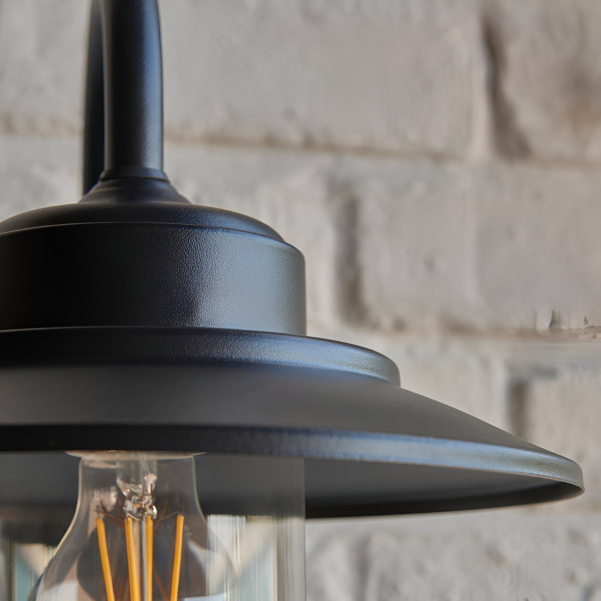 Close-up of the Endon Cranhurst outdoor wall light in matt black, showing the wide-brimmed shade, curved arm and clear glass dome with E27 filament bulb.