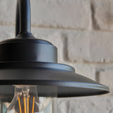 Close-up of the Endon Cranhurst outdoor wall light in matt black, showing the wide-brimmed shade, curved arm and clear glass dome with E27 filament bulb.