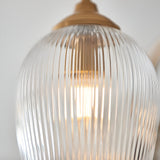 Close-up of Endon Halstead Ribbed semi-flush ceiling light showing a ribbed glass shade lit with a warm glow beneath an aged brass fitting.