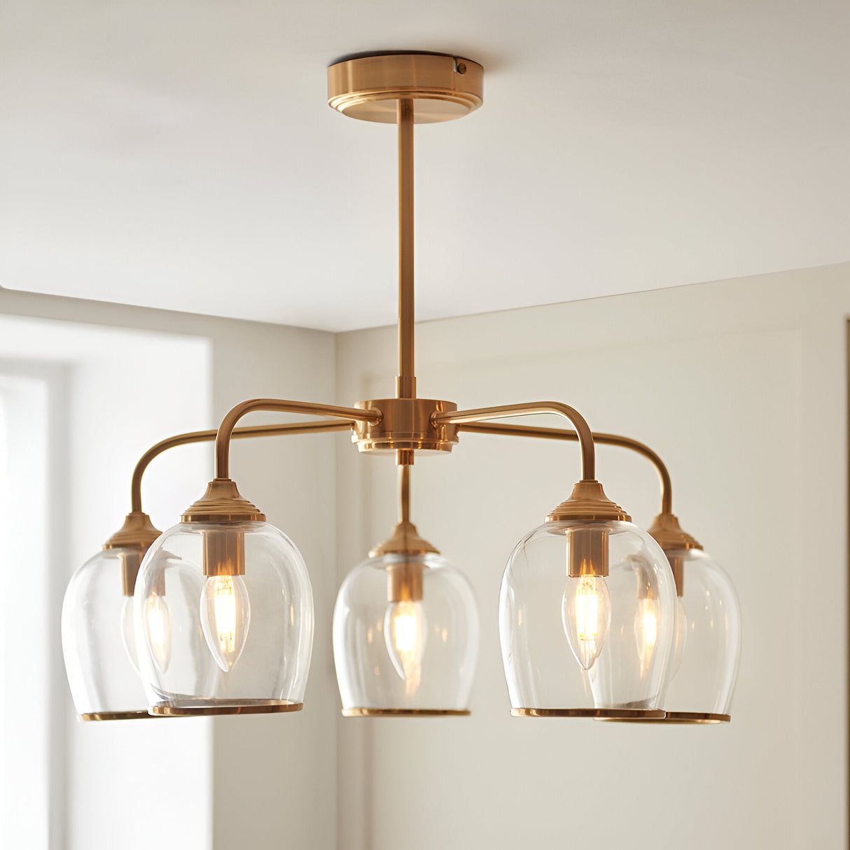 Halstead 5 Light Pendant in brass with arched arms and clear glass shades edged in metal trim, shown fitted to a ceiling in a light-toned room.