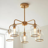 Halstead 5 Light Pendant in brass with arched arms and clear glass shades edged in metal trim, each showing a filament bulb, shown against a light ceiling.