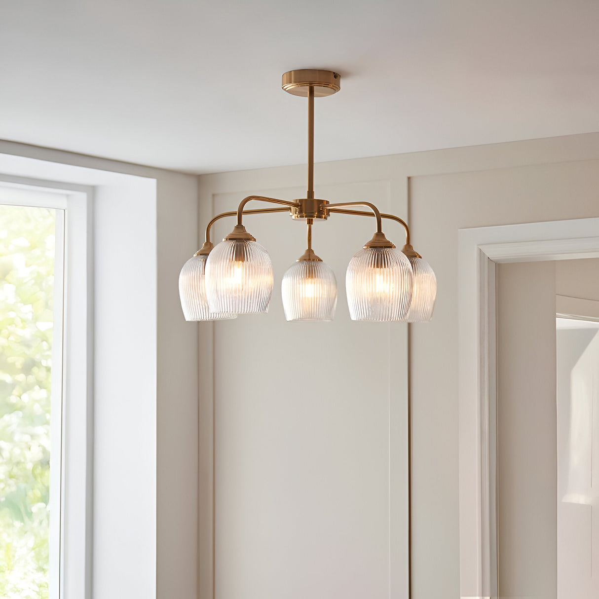 Endon Halstead Ribbed 5 Light semi-flush pendant in brushed brass with fluted clear glass shades on curved arms, installed in a bright neutral room.