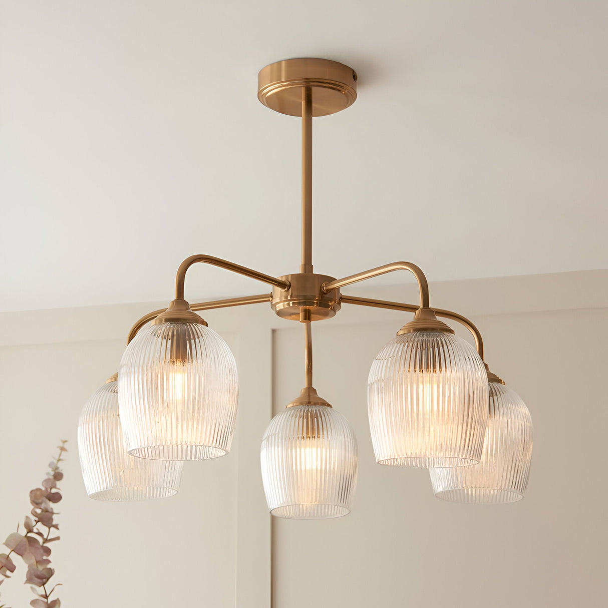 Endon Halstead Ribbed 5 Light semi-flush pendant in brushed brass with fluted clear glass shades on curved arms, installed against a pale wall.
