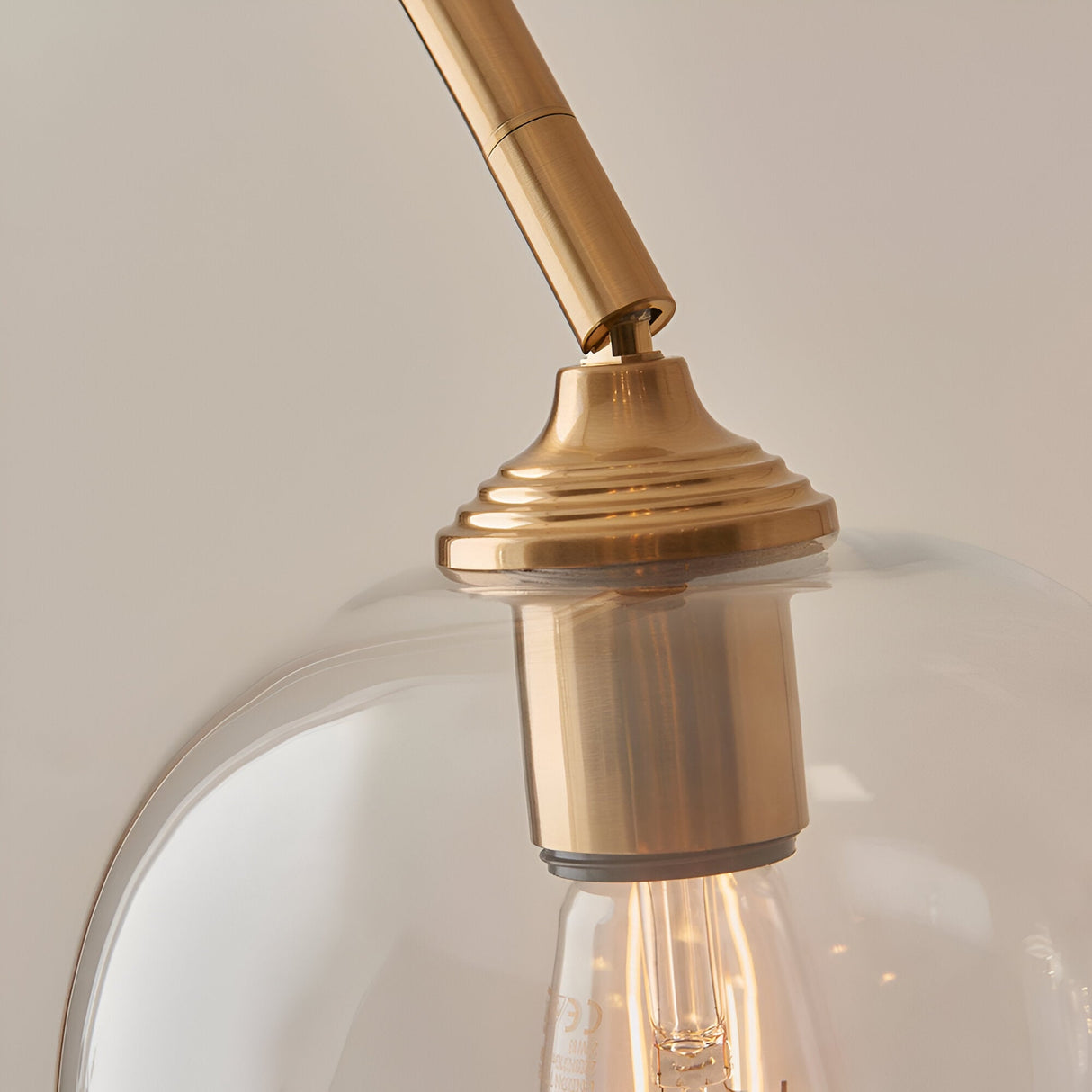 Halstead Floor Lamp in aged brass, close-up of the curved stem and ribbed fitting holding a clear domed glass shade with visible filament bulb.