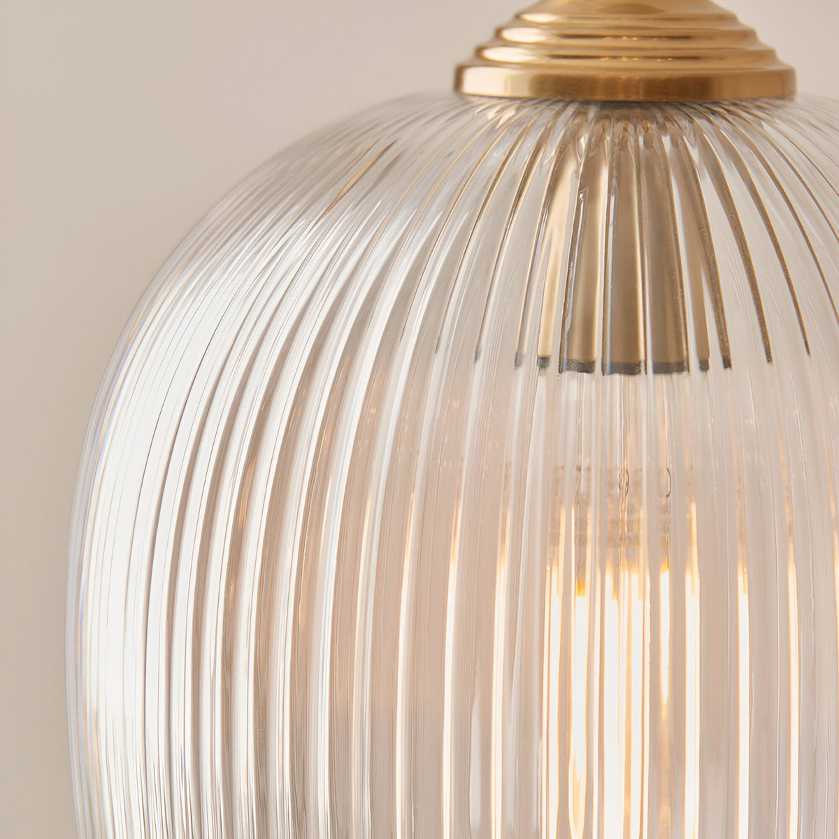 Close-up of the Endon Halstead Ribbed Floor Lamp's domed fluted glass shade and aged brass fitting, with a filament bulb glowing inside.