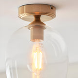 Halstead Flush Ceiling Light in aged brass, close-up of the round mount and clear glass globe shade with visible E27 filament bulb.